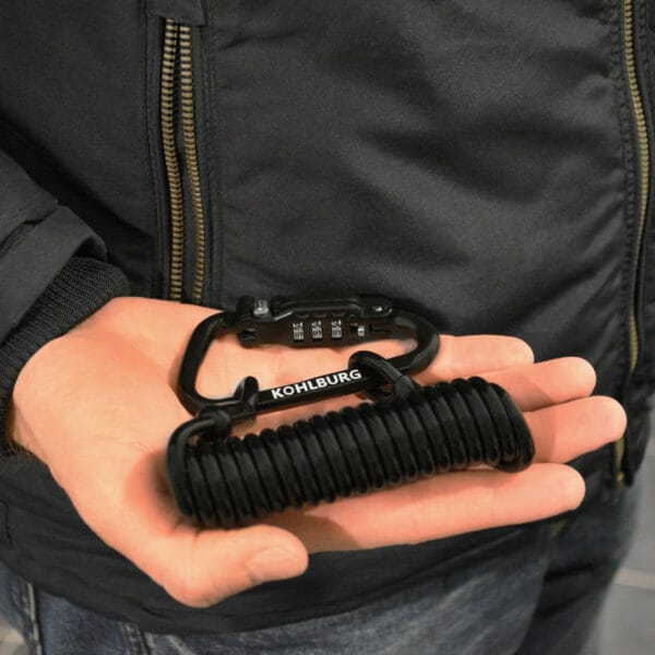 Eine Person hält ein Premium Kabelschloss mit Zahlenkombination "Zermatt" und Spiralkabel in der Hand.