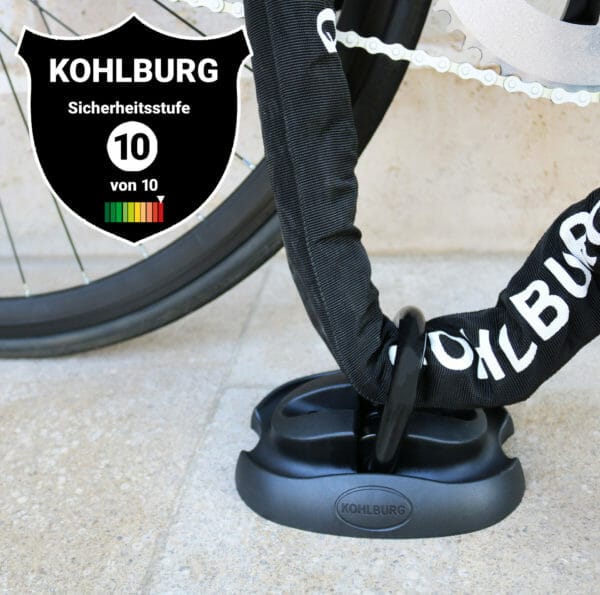 Der KOHLBURG Sicherheits-Bodenanker "London" sichert ein Fahrradrad an einem Bodenanker; Sicherheitsstufe 10/10 dargestellt.