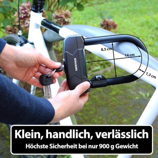 Eine Person sichert ein weißes Fahrrad mit dem Leichtes Sicherheits Bügelschloss "Budapest" (schwarzes Schloss); der deutsche Text und die Abmessungen des Schlosses sind auf dem Bild zu sehen.