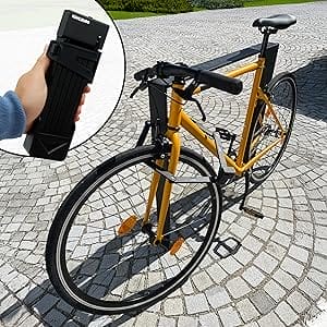 Gelbes Fahrrad auf Kopfsteinpflaster, in der Mitte eine Hand, die ein schwarzes Catania-Klappradschloss hält.